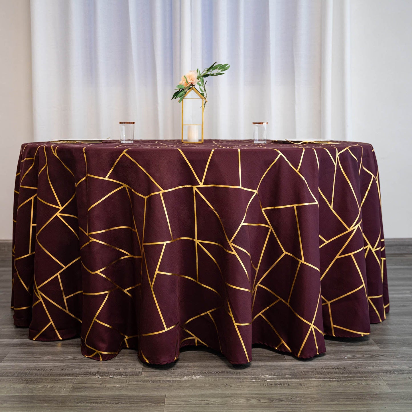Burgundy round tablecloth with gold foil geometric pattern.