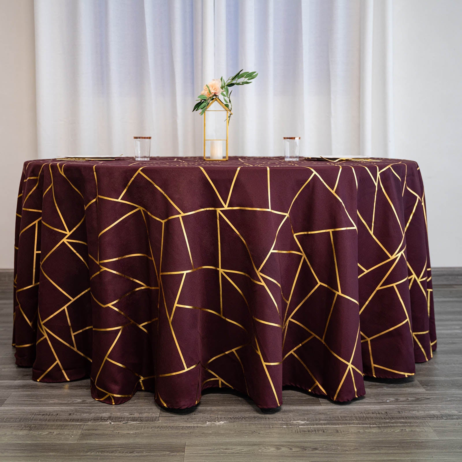 Burgundy round tablecloth with gold foil geometric pattern.