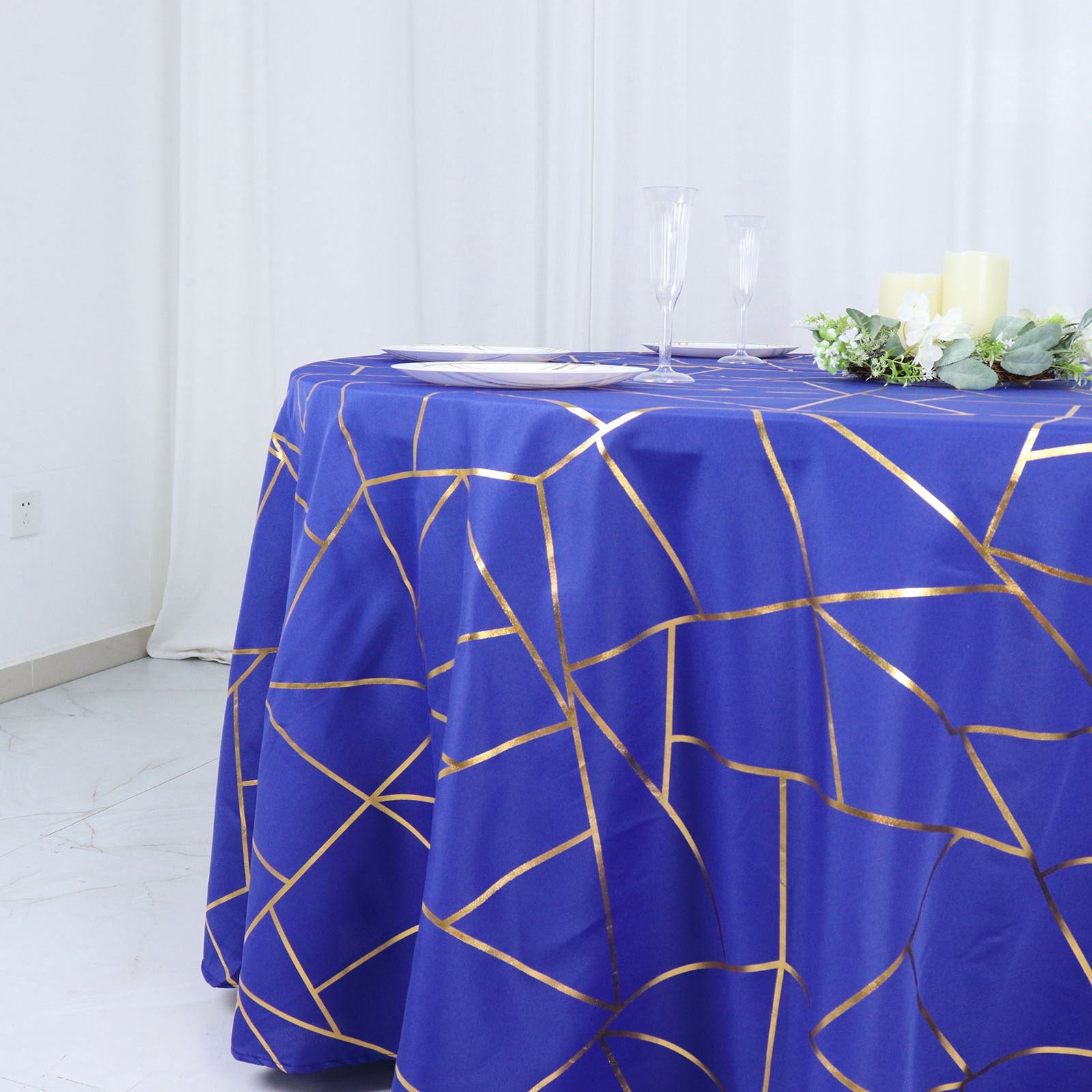 Royal blue round tablecloth with gold foil geometric pattern.