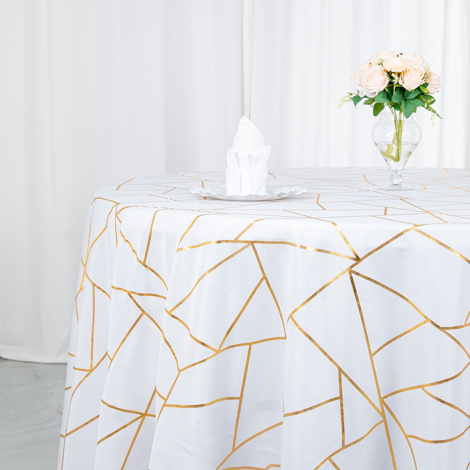 White tablecloth with gold foil geometric pattern on a round table.