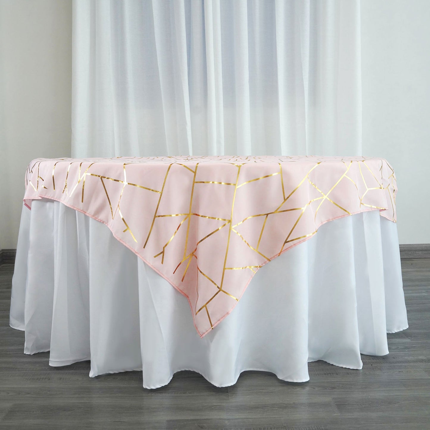 Blush square table overlay with gold foil geometric pattern.