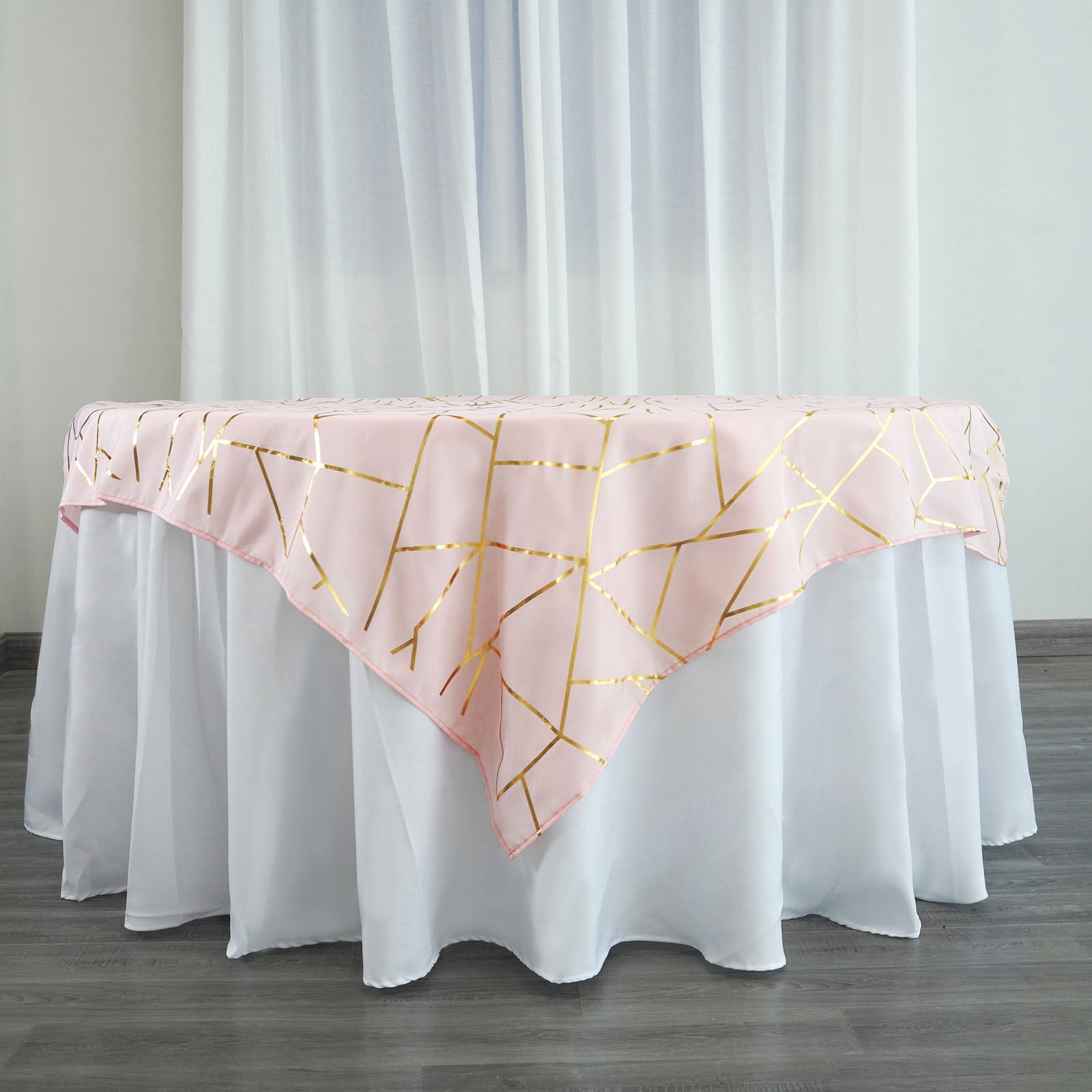 Blush square table overlay with gold foil geometric pattern.