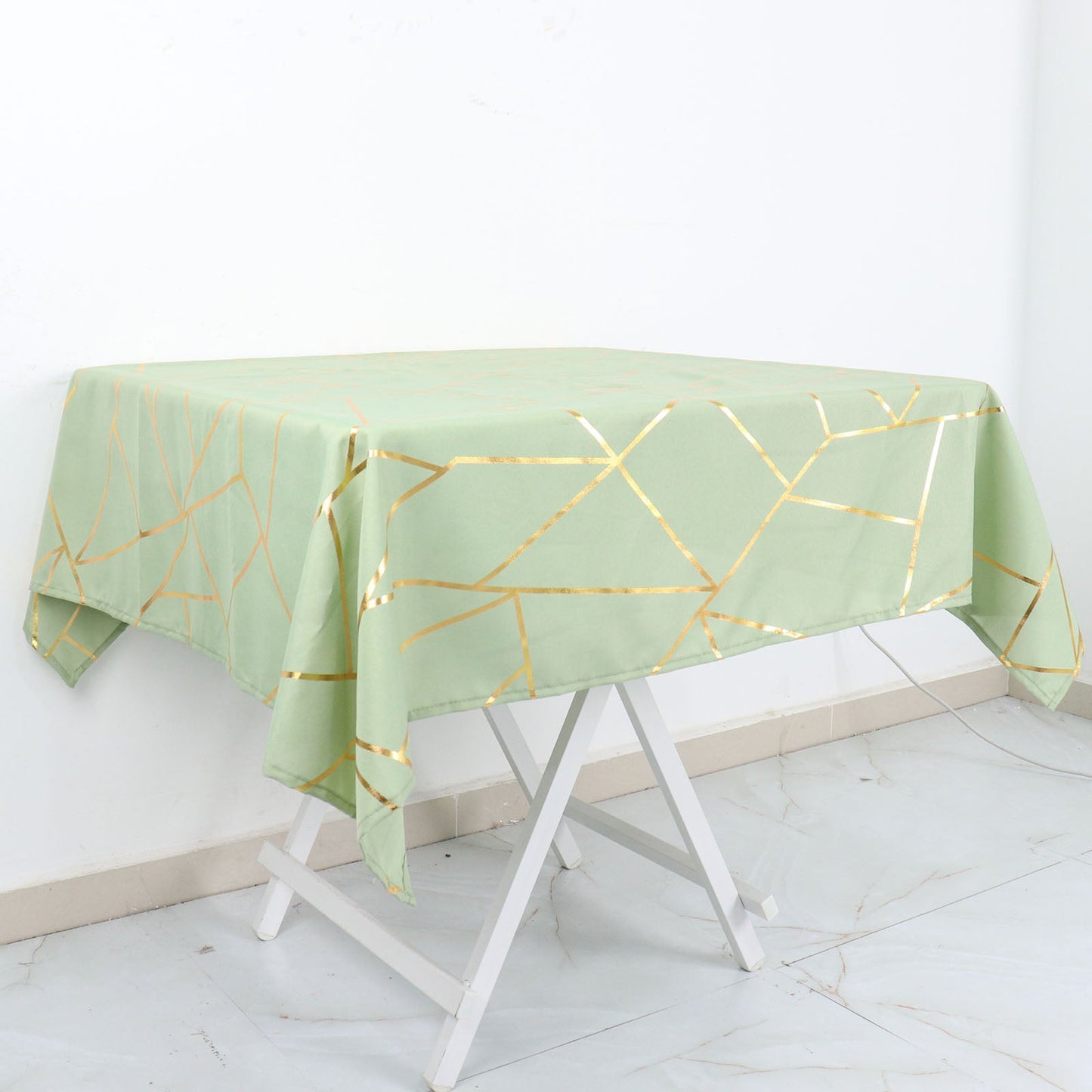Sage green square table overlay with gold foil geometric pattern.