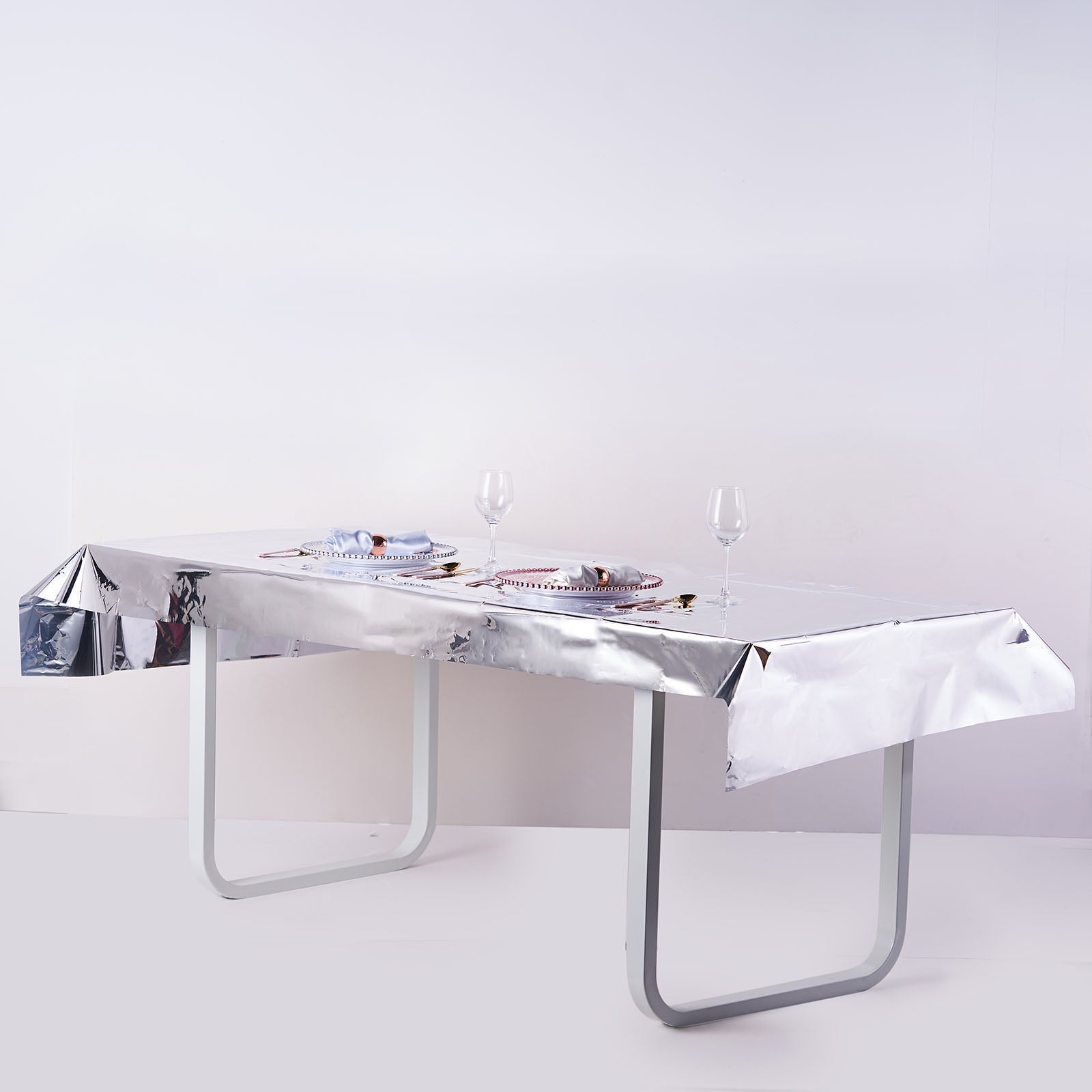Silver metallic foil tablecloth on a rectangular table setting.
