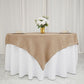 Natural faux burlap square table overlay on a white tablecloth with flowers.