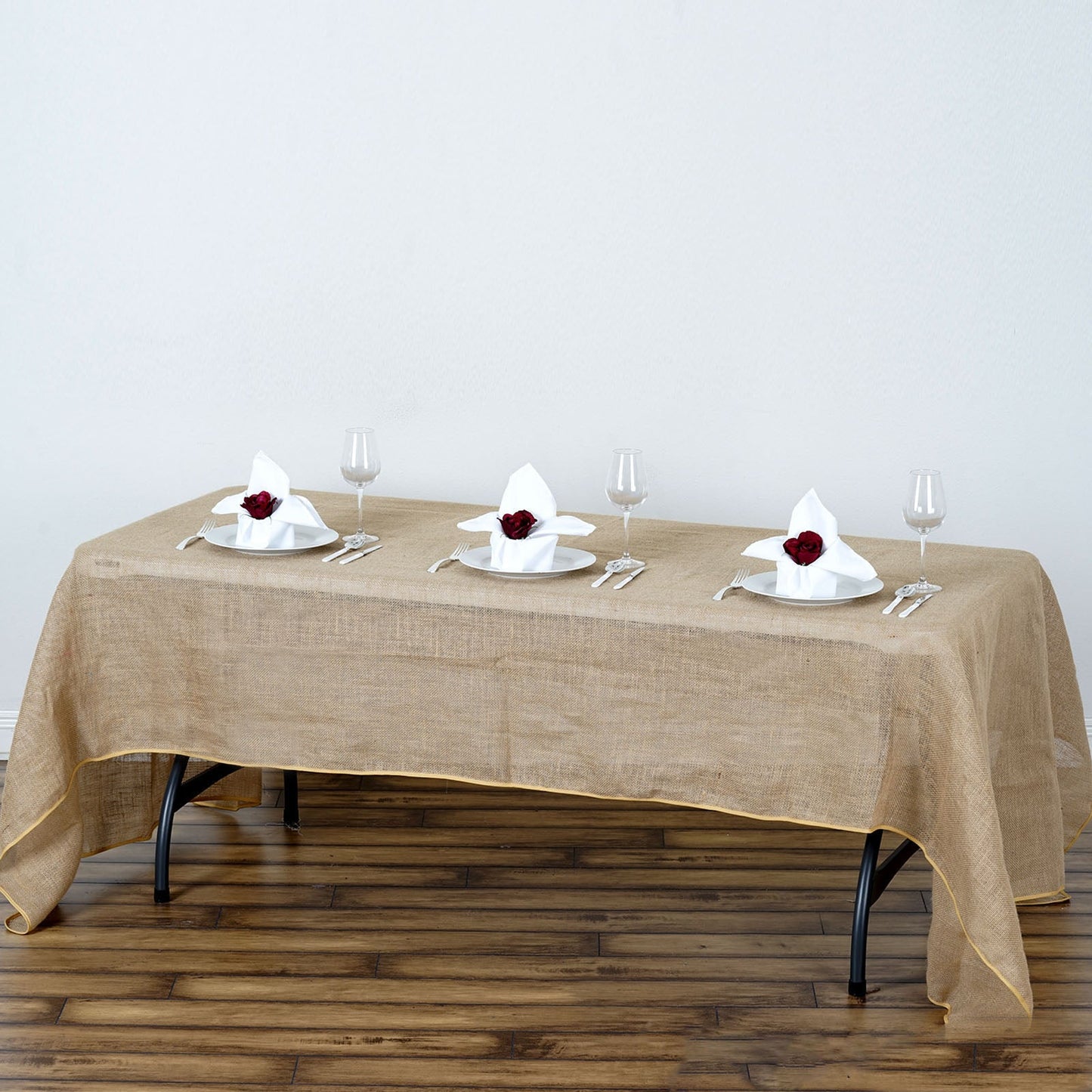 Natural rustic burlap tablecloth on a wooden table with elegant place settings.