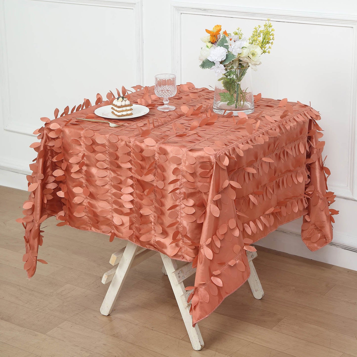 Terracotta 3D leaf petal taffeta fabric table overlay on a wooden table.