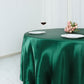 Emerald green satin round tablecloth on a dining table.