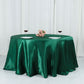 Hunter emerald green satin round tablecloth on a table with wine glasses and flowers.