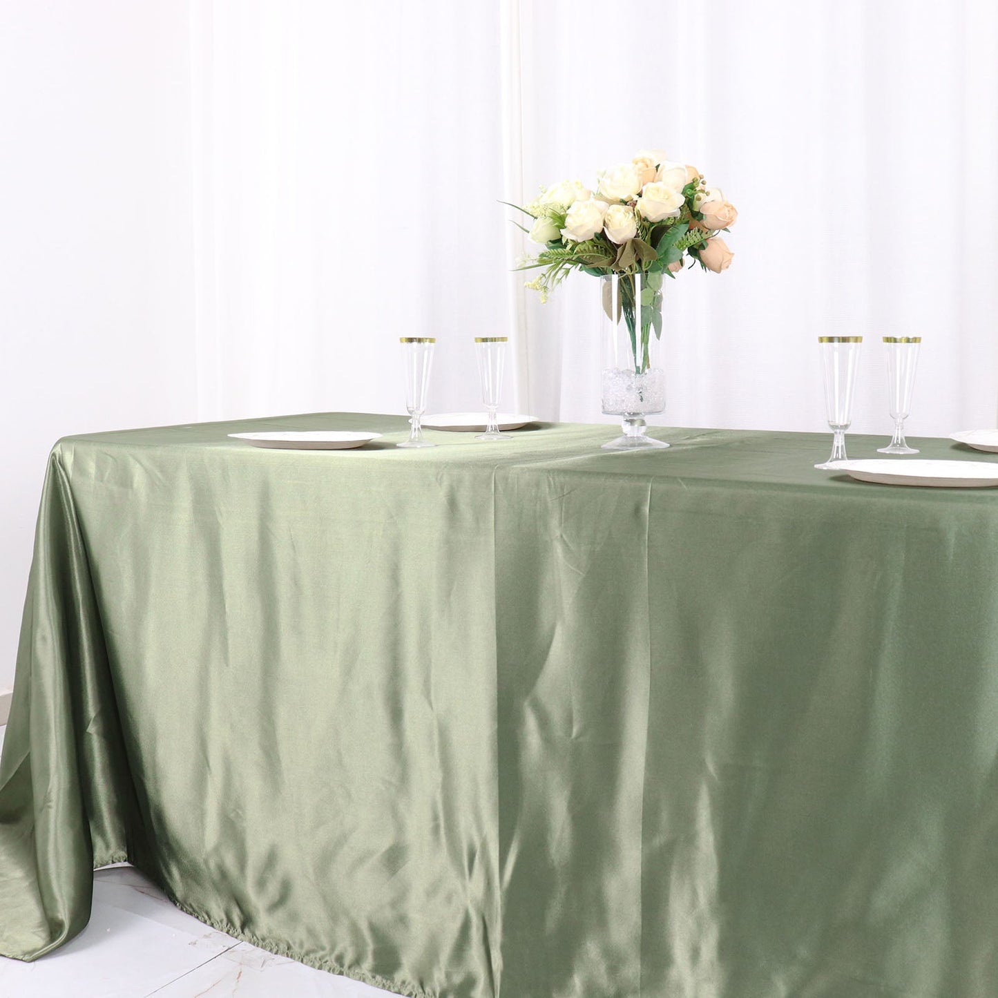 Dusty sage green satin rectangular tablecloth on a table with floral centerpiece.