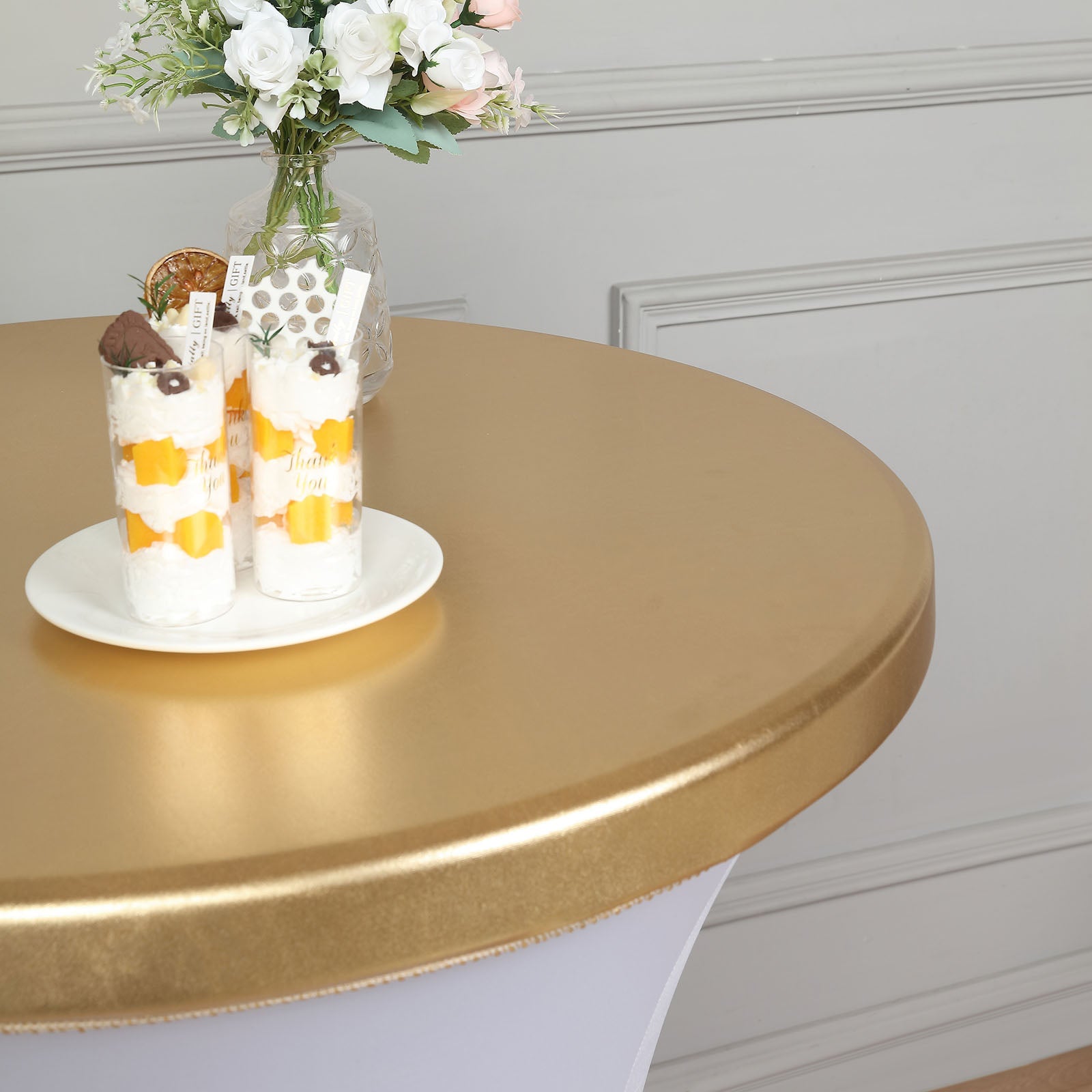 Metallic gold cocktail table cover with desserts on top.