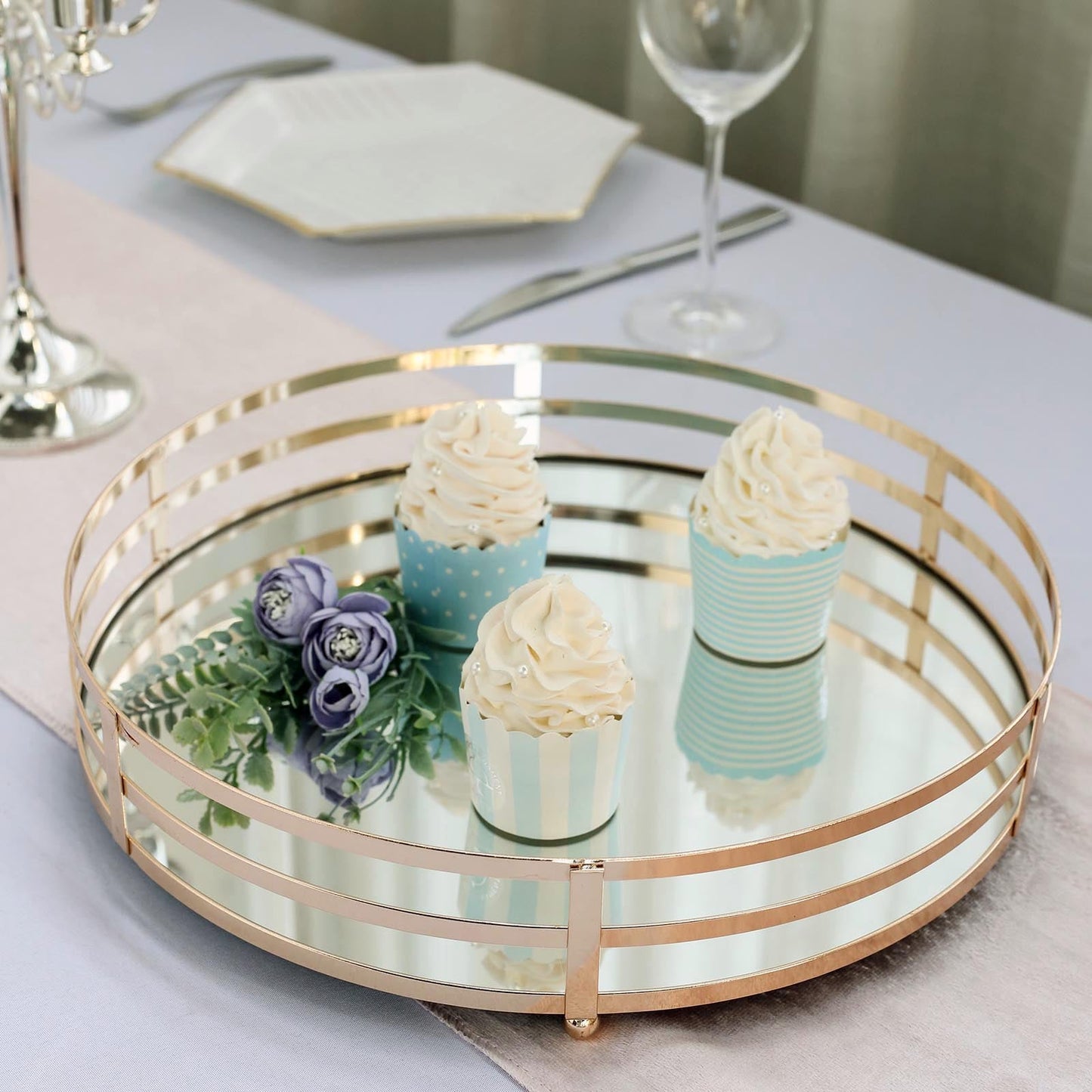 Gold metal round mirror serving tray with decorative cupcakes.