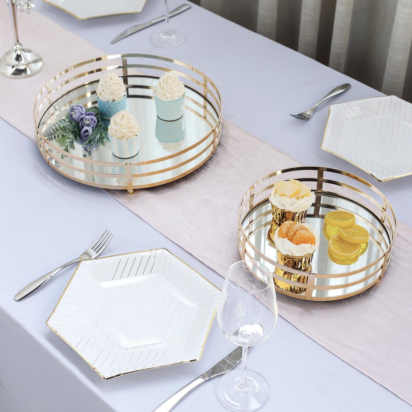 Gold round mirror serving trays on a table with desserts and flowers.