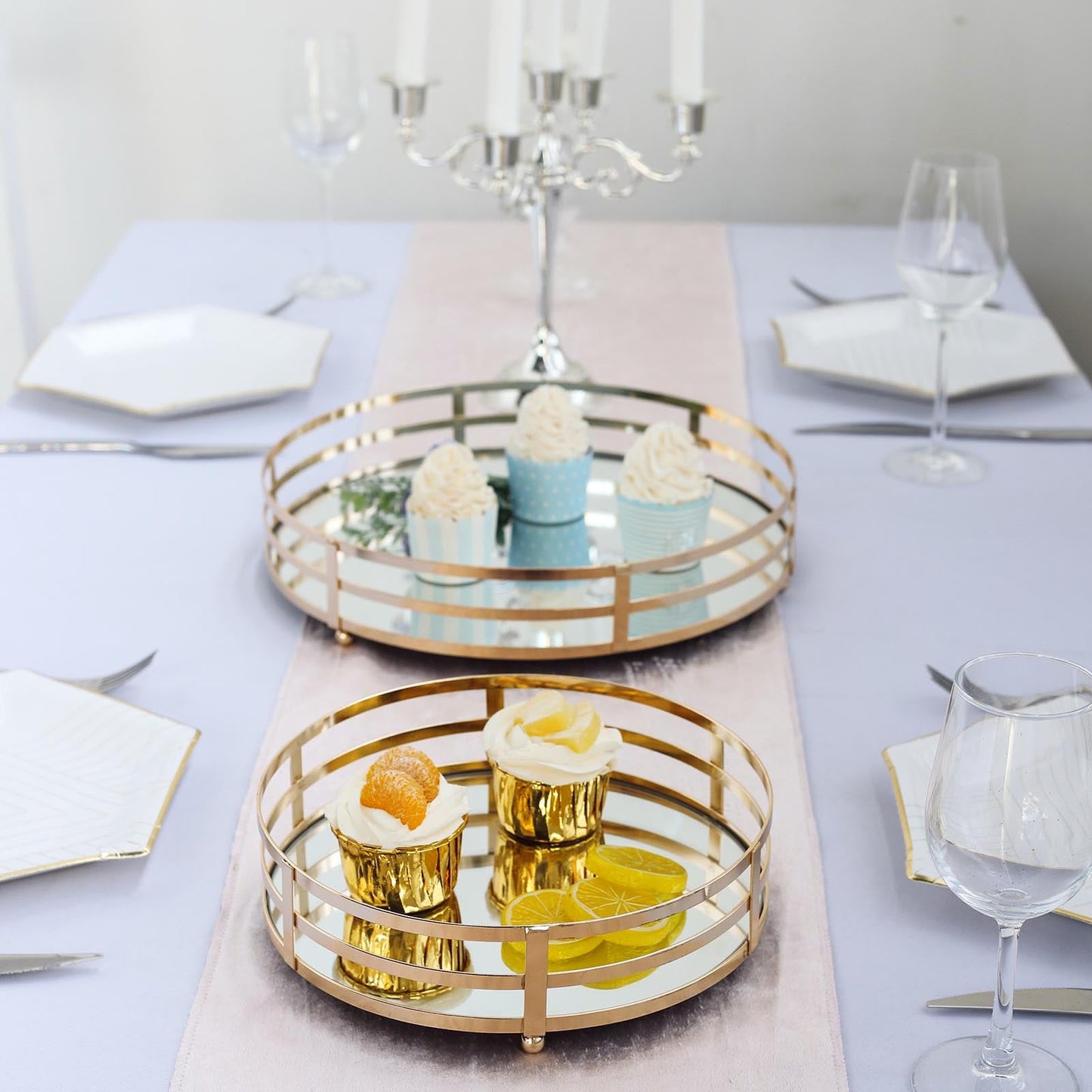 Gold metal round mirror vanity serving trays with desserts on a table.