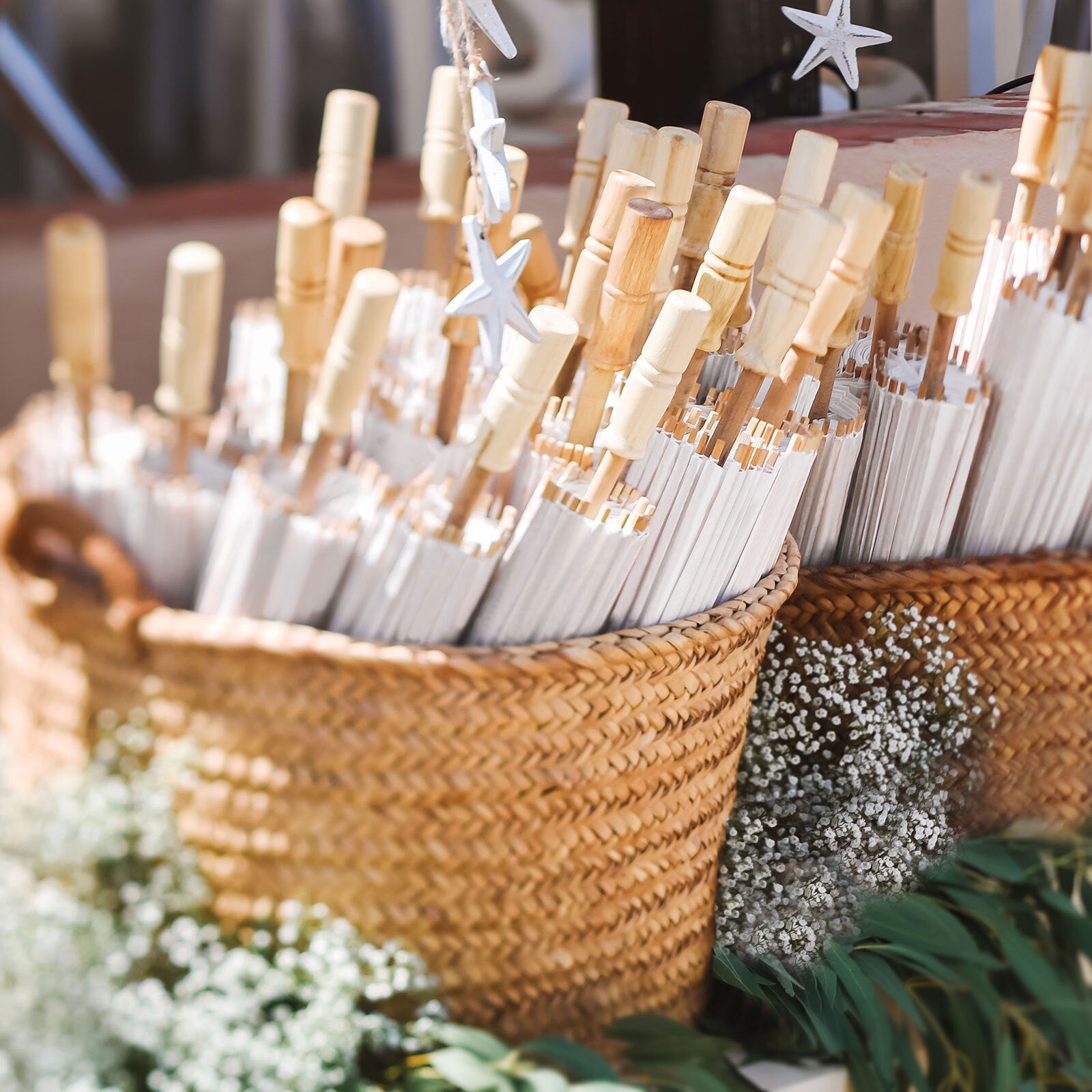 White bamboo umbrellas in woven baskets, perfect for wedding decor and party favors.