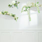 White parasol umbrellas decorated with flowers, hanging in a bright space.