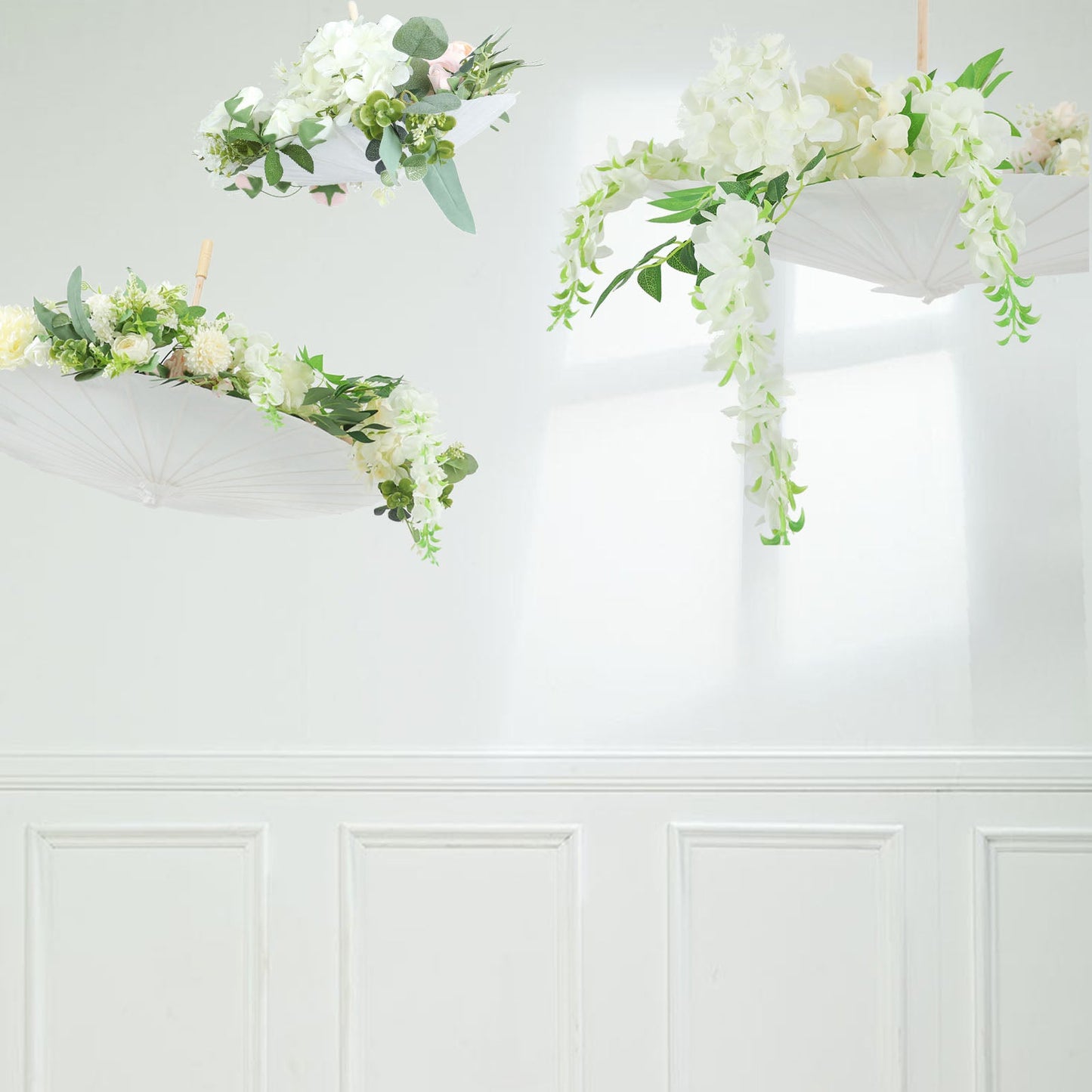 White parasol umbrellas decorated with flowers, hanging in a bright space.