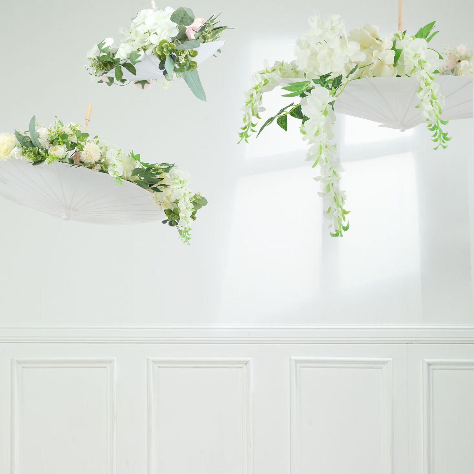 White parasol umbrellas decorated with flowers, hanging in a bright space.