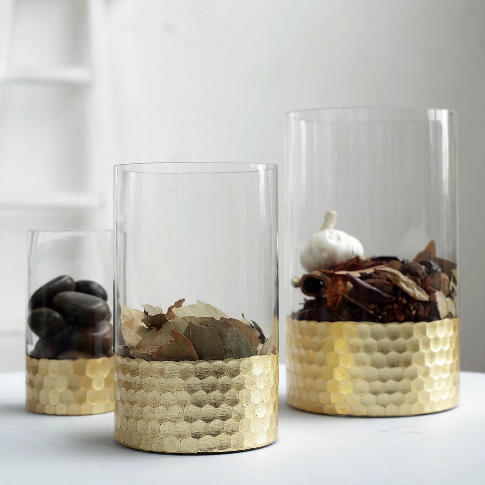 Set of 3 glass cylinder vases with gold honeycomb base, ideal for candles or decor.