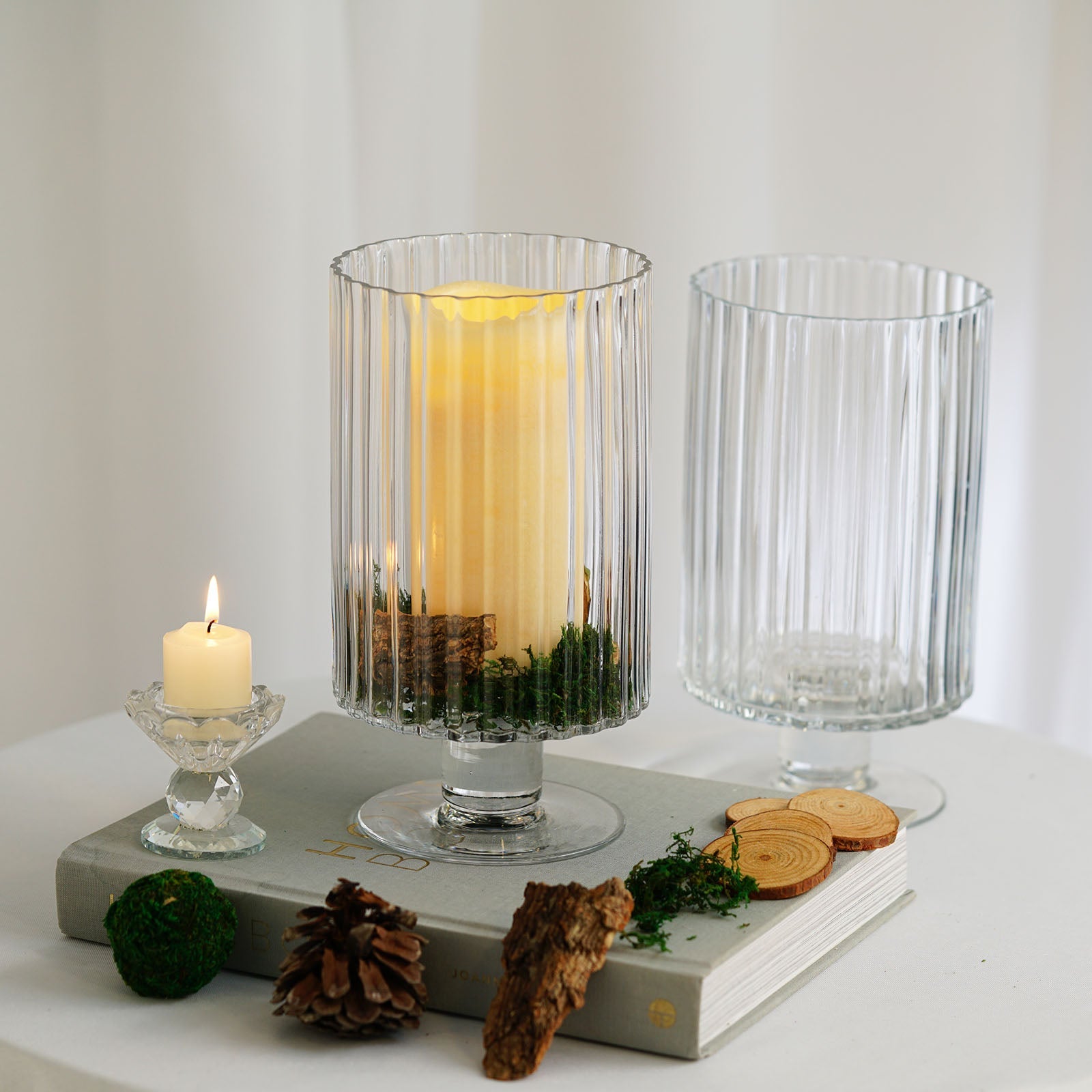 Clear ribbed glass vases on a table with candles and decorative elements.