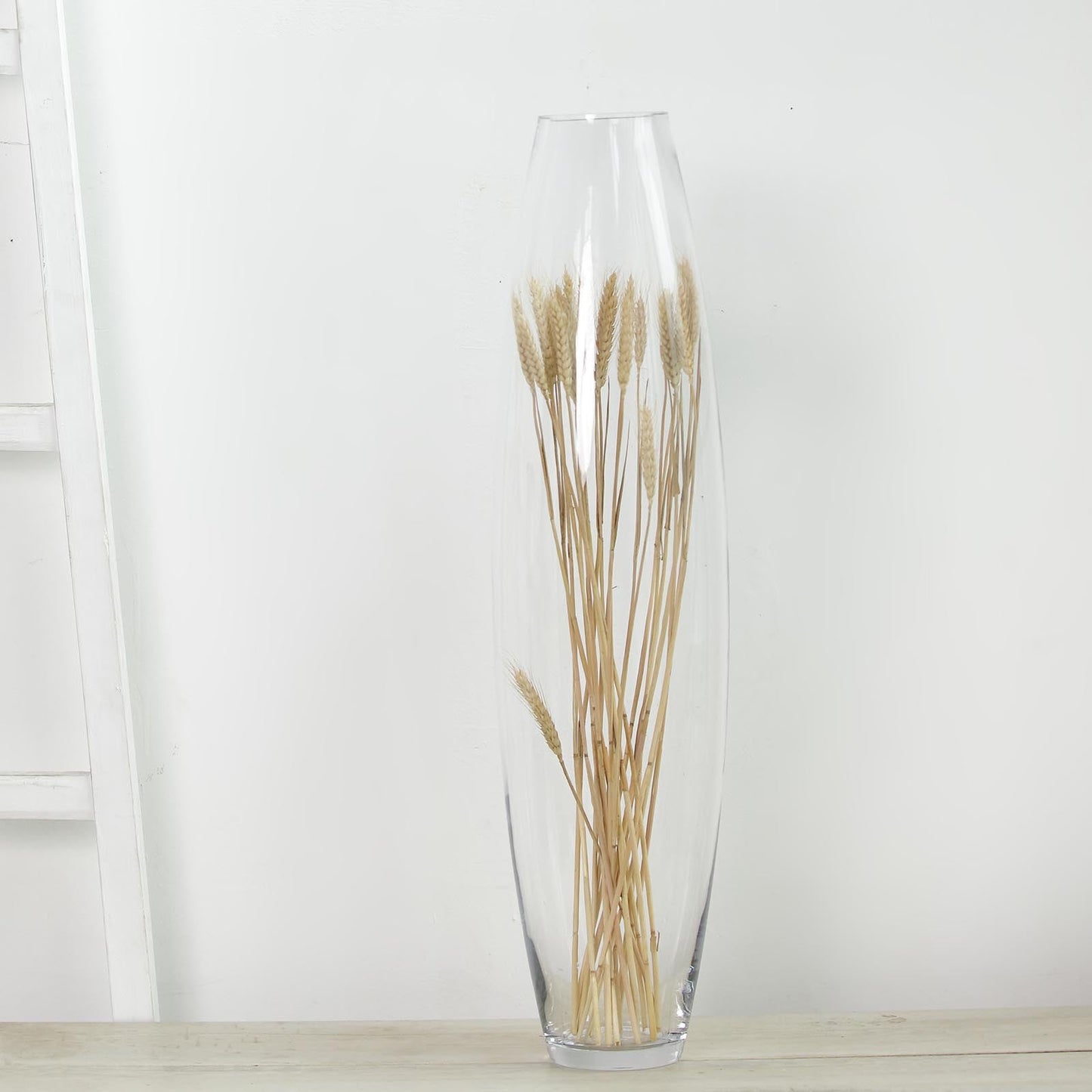 Clear vase with dried wheat stems, perfect for home decor.