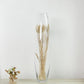 Elegant glass vase with dried wheat grass and a small floral arrangement.