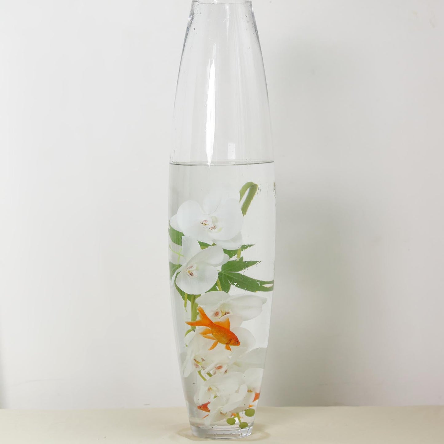 Elegant vase with water, white flowers, and a goldfish for a serene decor.
