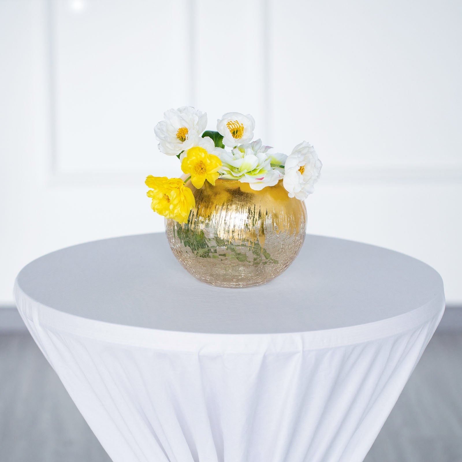Gold foiled crackle glass bubble vase with flowers on a table.
