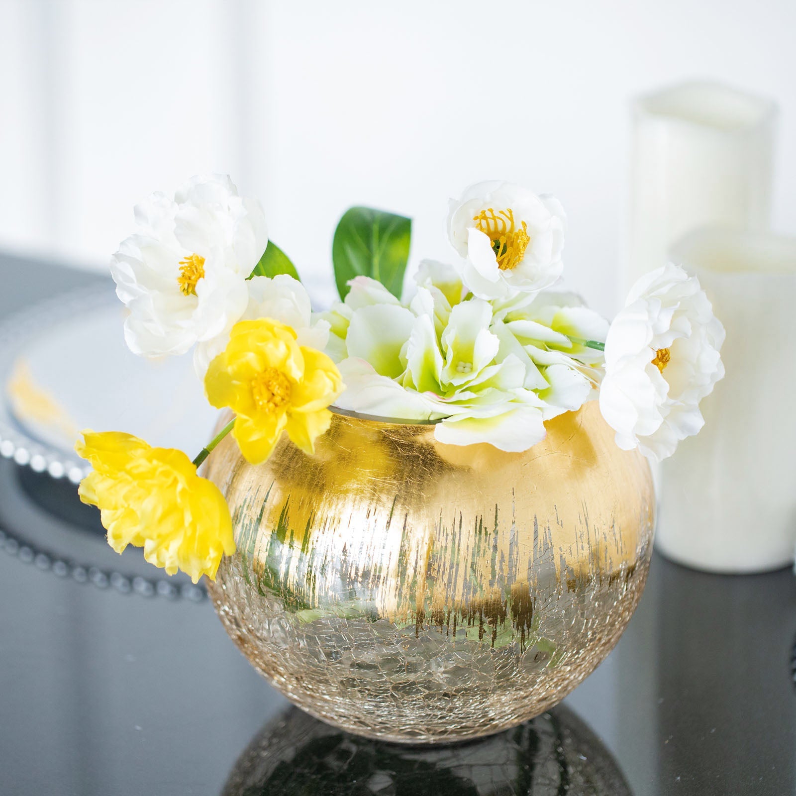 Gold foiled crackle glass bubble vase with white and yellow flowers.