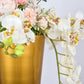 Brushed gold metal trumpet vase with floral arrangement.