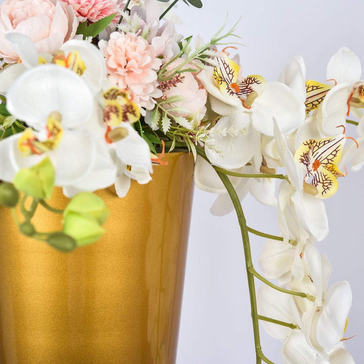 Brushed gold metal trumpet vase with floral arrangement.