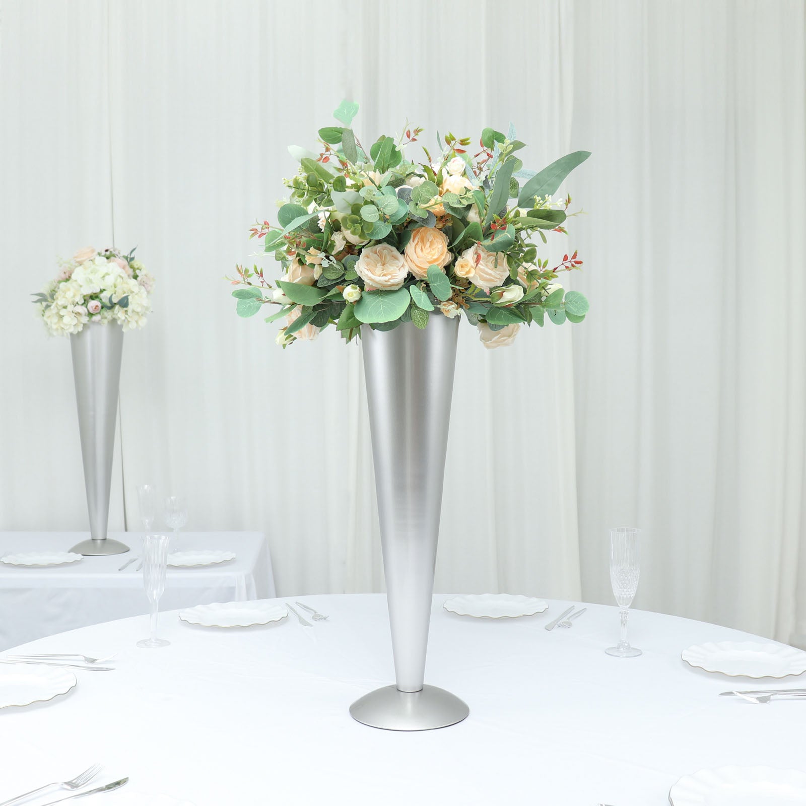 Brushed silver metal trumpet flower vase with floral arrangement centerpiece.