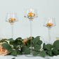Clear glass tealight holders with gold candles, elegant table centerpiece.
