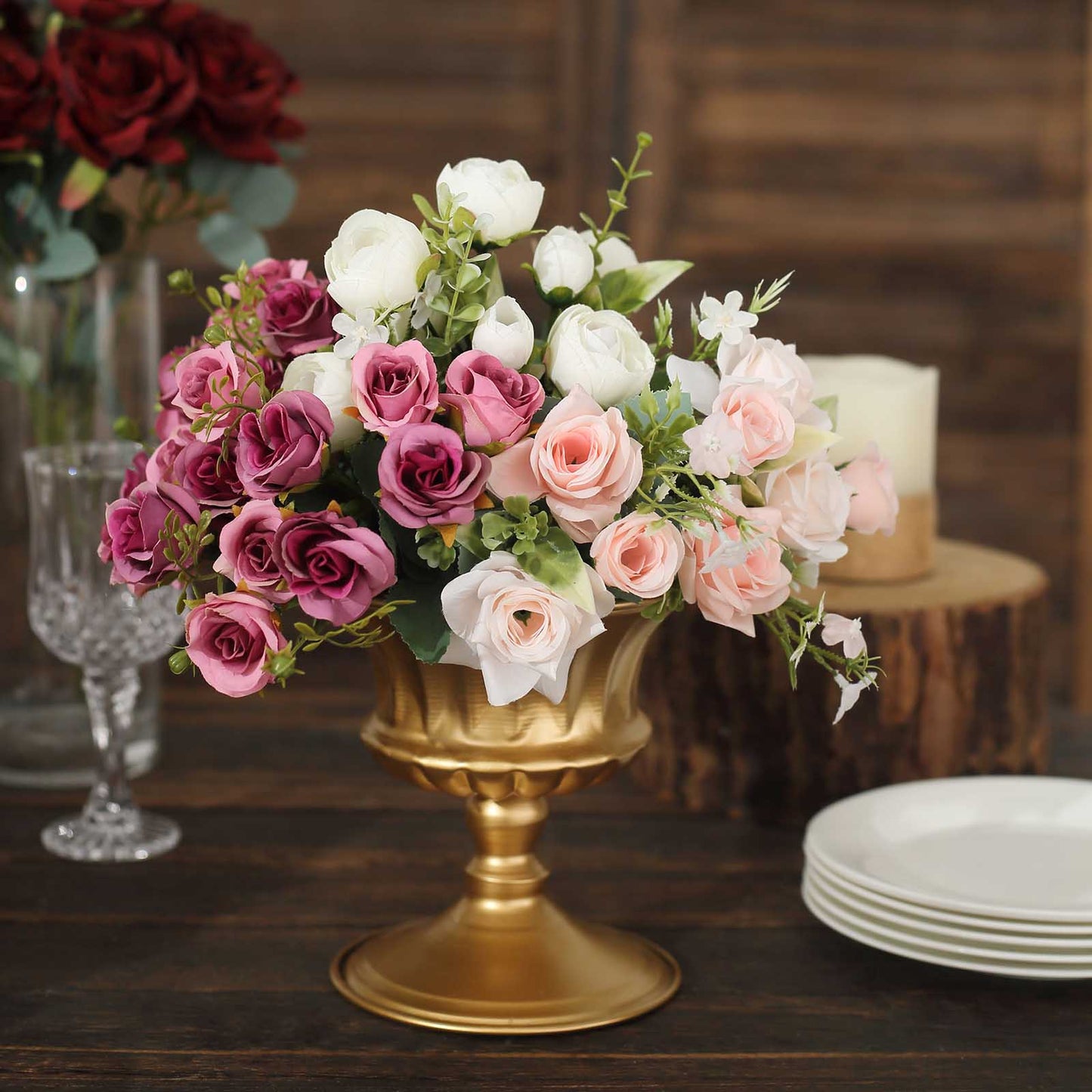 Gold metal pedestal vase with a floral arrangement of pink and purple roses.