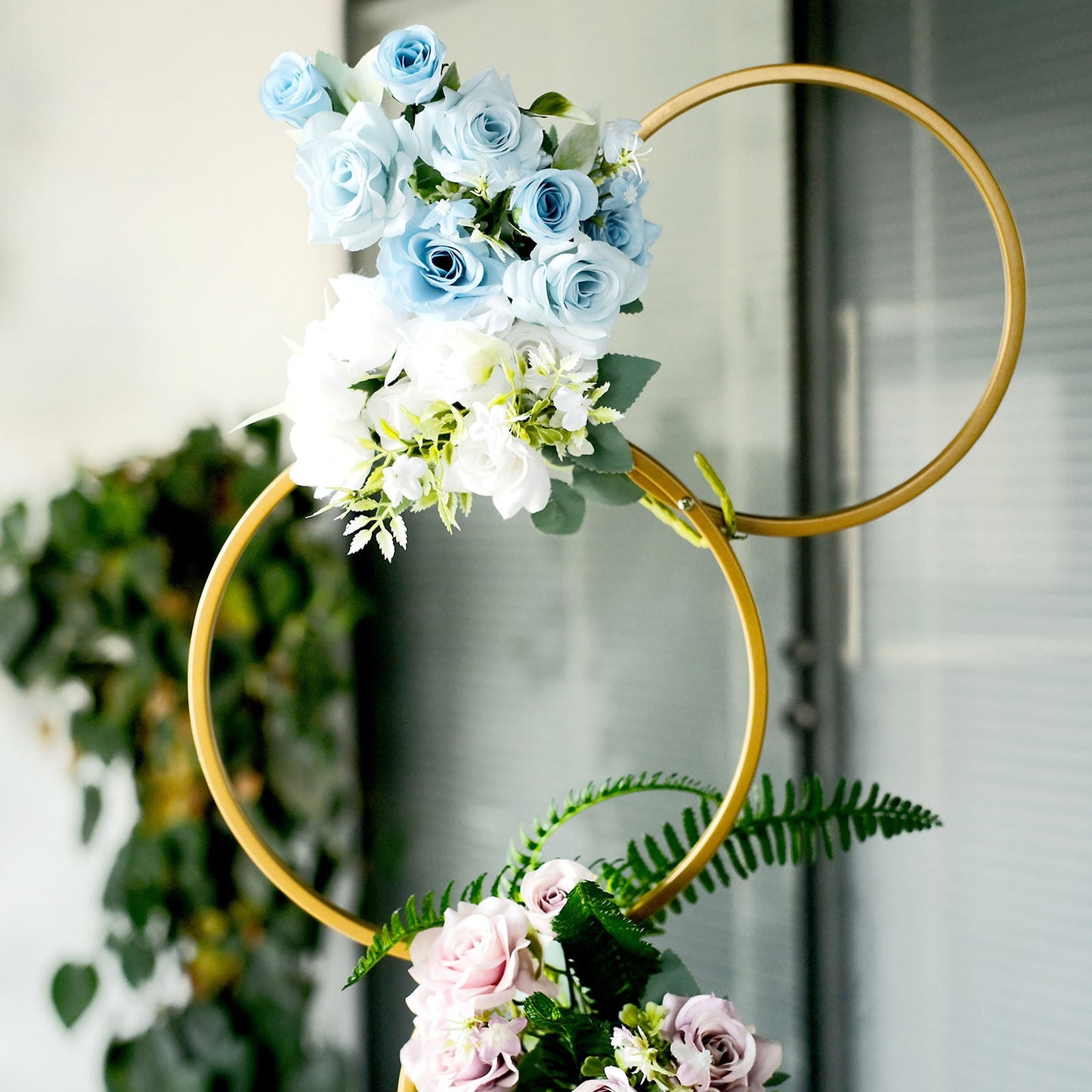 Gold metal hoop flower stand with blue and white floral arrangement.