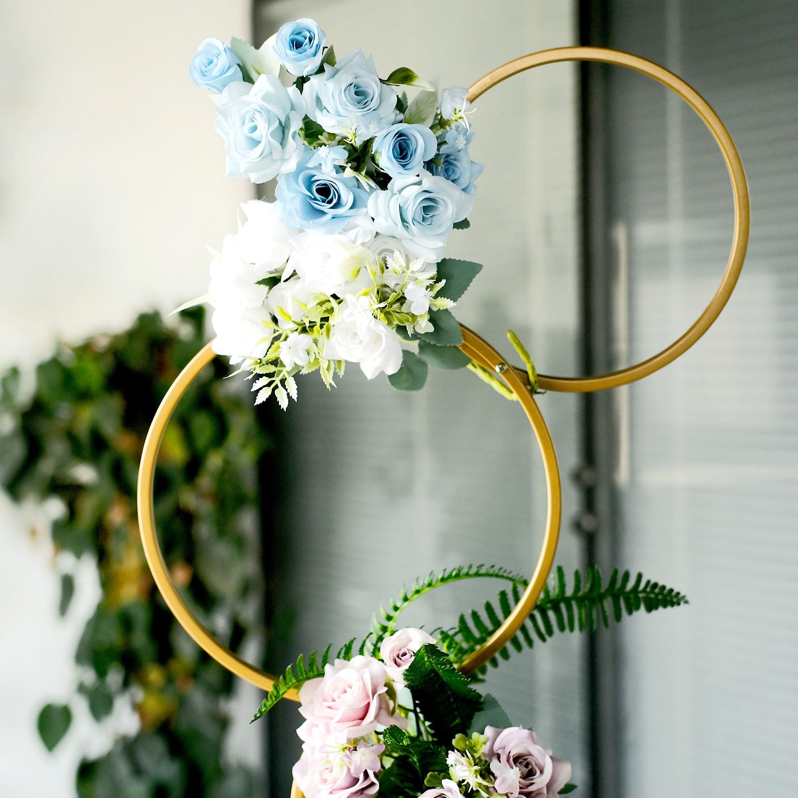 Gold metal hoop flower stand with blue and white floral arrangement.