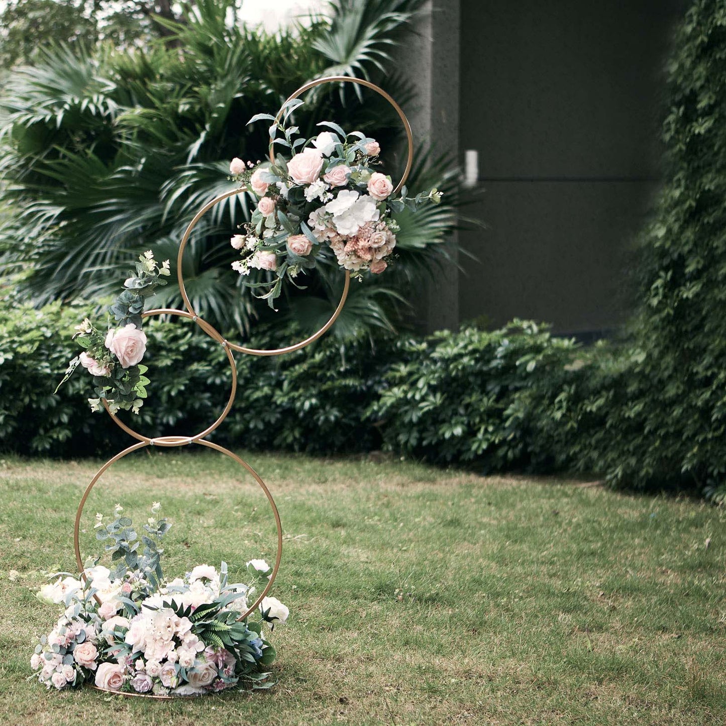 Gold 4-tiered hoop flower stand with floral arrangement for weddings.
