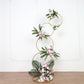 Gold hoop pillar flower stand with floral arrangements.
