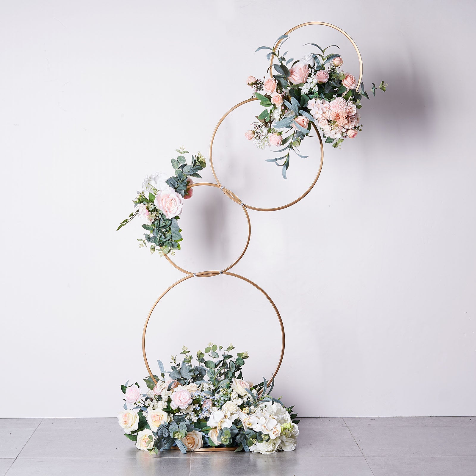 Gold hoop pillar flower stand with floral arrangements for weddings.