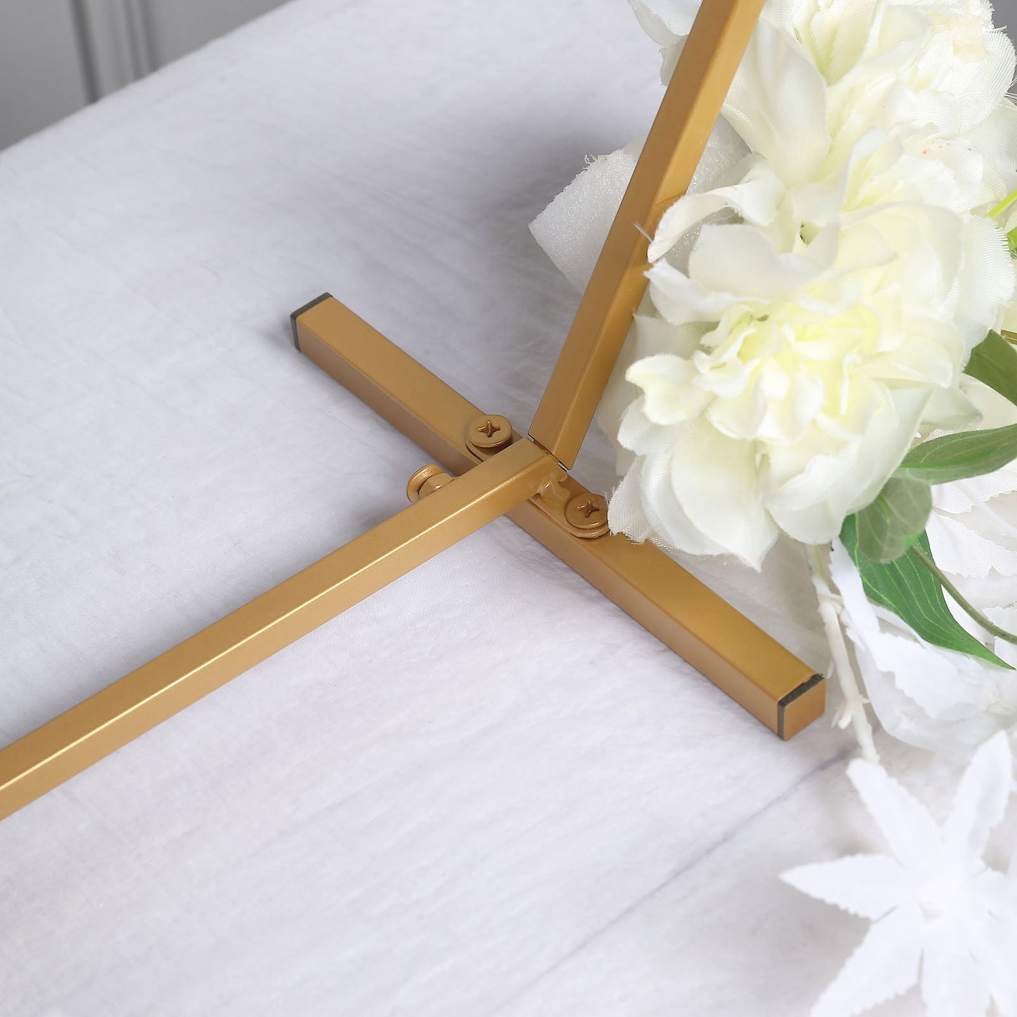 Gold metal hexagon table wedding arch centerpiece stand with floral accents.