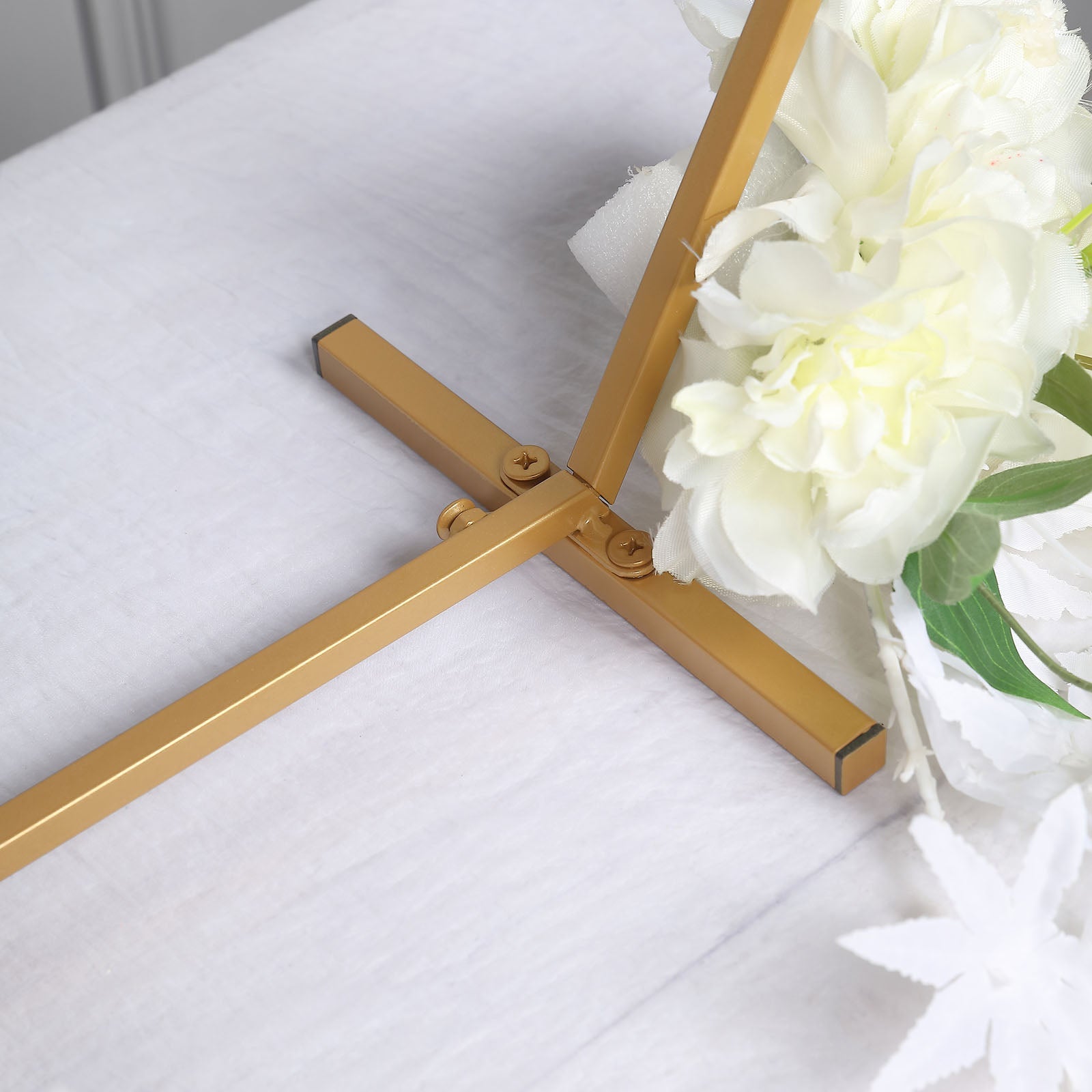 Gold metal hexagon table wedding arch centerpiece stand with floral accents.