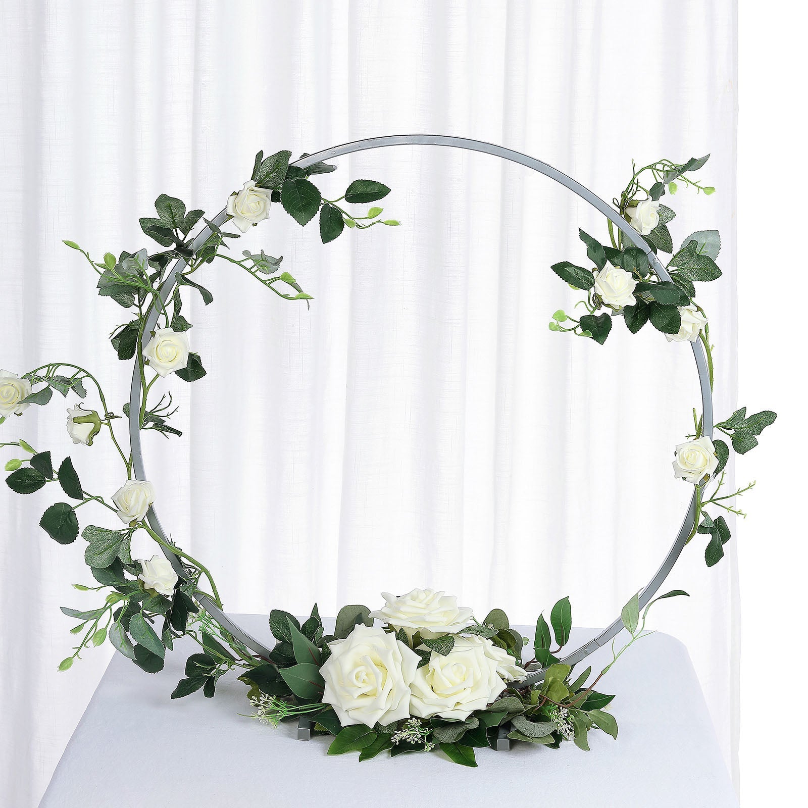 Silver round arch wedding centerpiece with white roses and greenery.