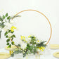 Gold metal round hoop floral centerpiece with white and yellow flowers.