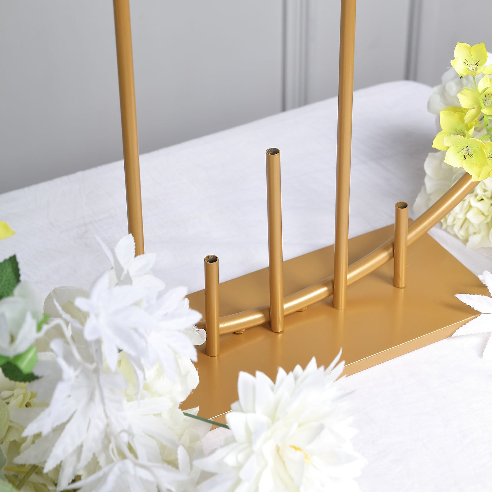 Gold floral hoop wedding centerpiece with pillars and white flowers.