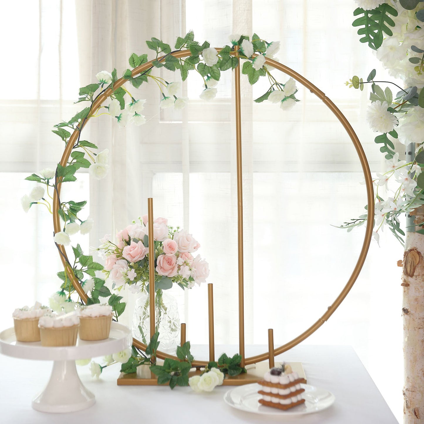 Gold floral hoop wedding centerpiece with pillars and greenery.