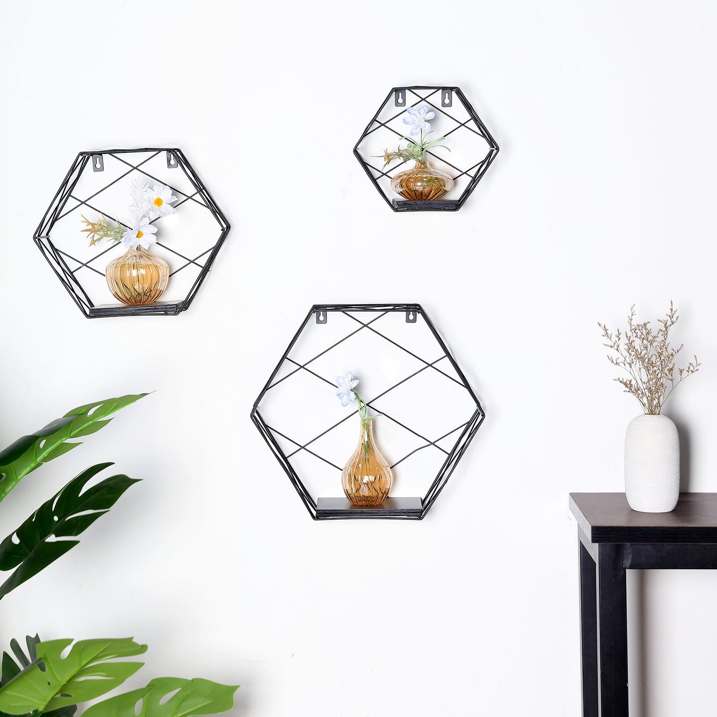 Black hexagonal floating wall shelves with decorative plants and vases.