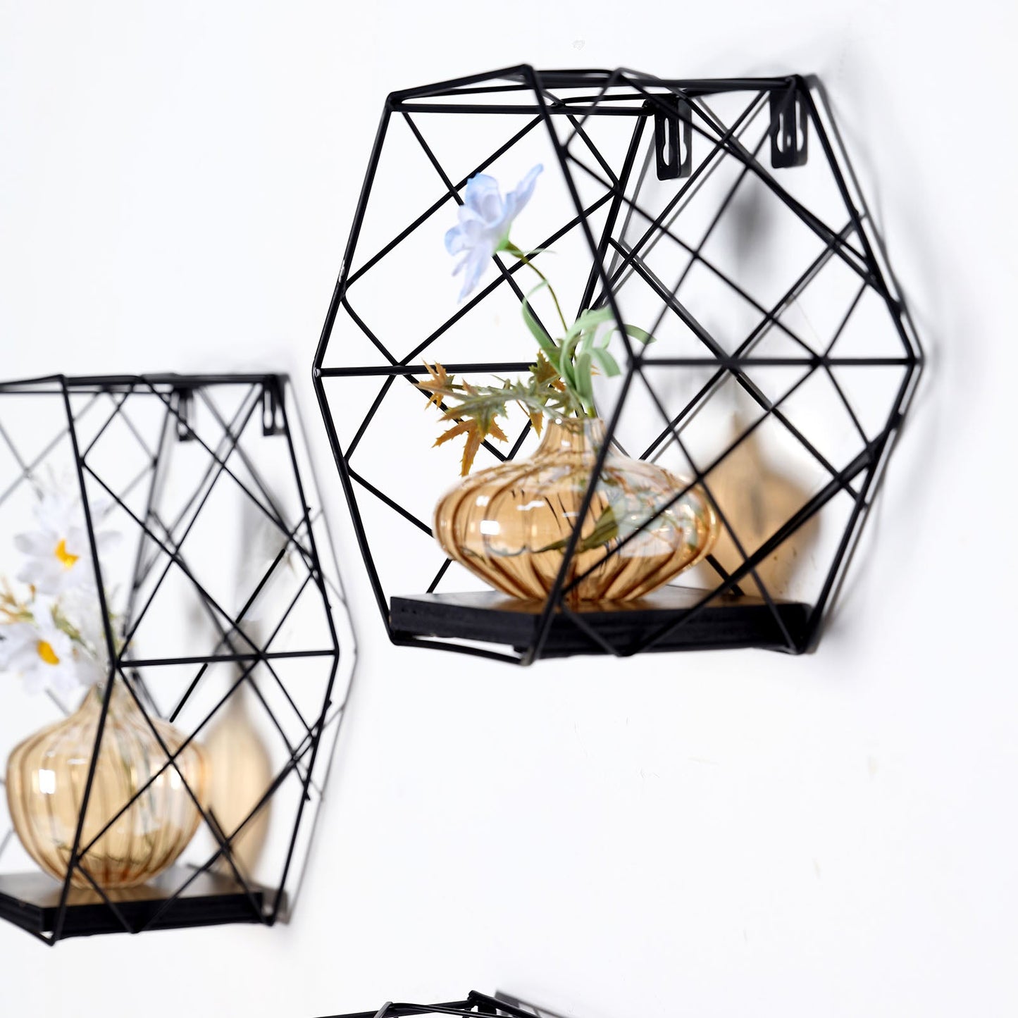 Black hexagonal floating wall shelves with decorative vases.