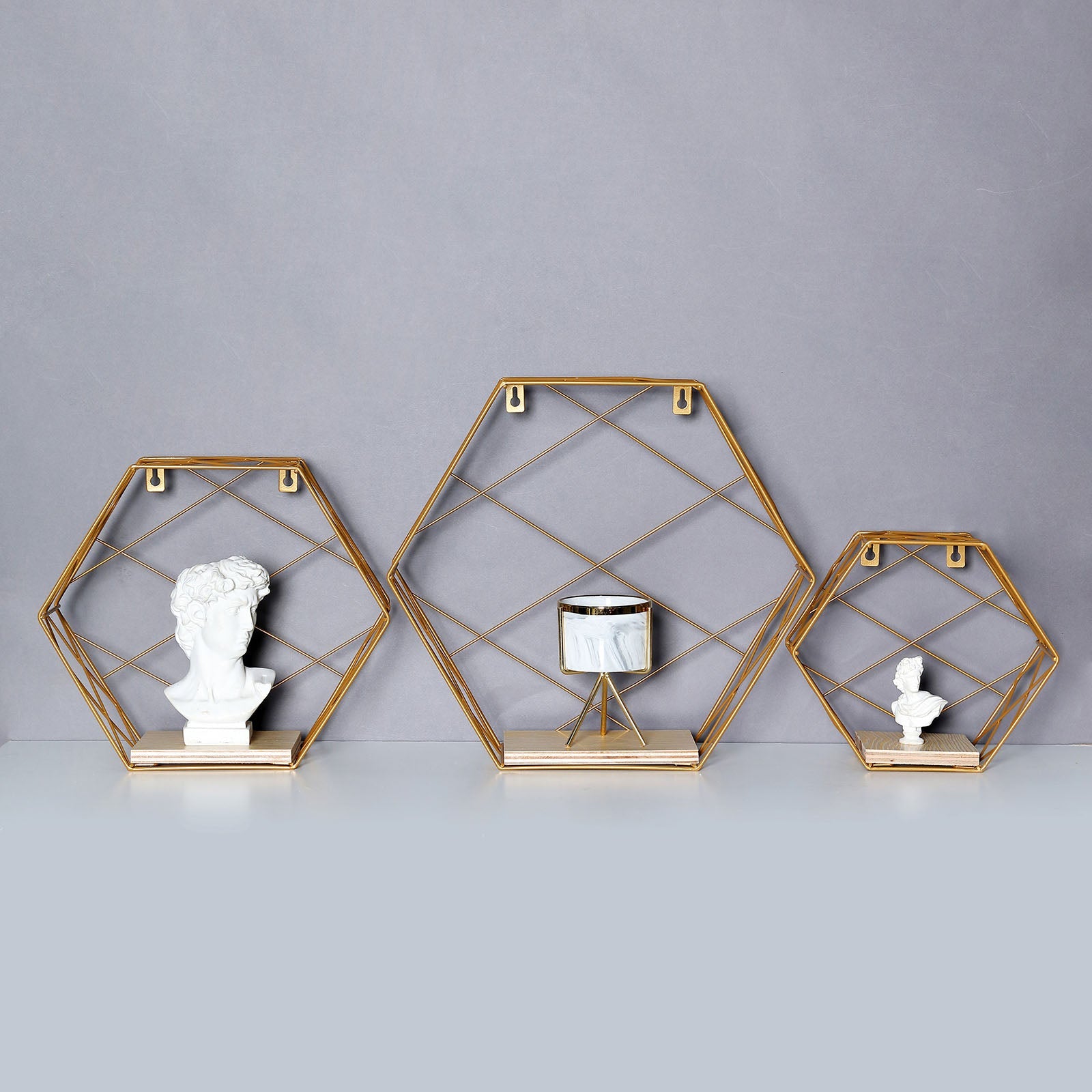 Gold hexagonal floating wall shelves with decorative items.