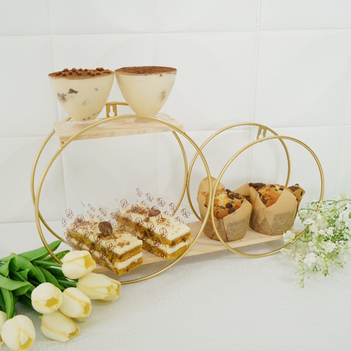 Gold 2-tier round floating shelf displaying desserts and pastries.