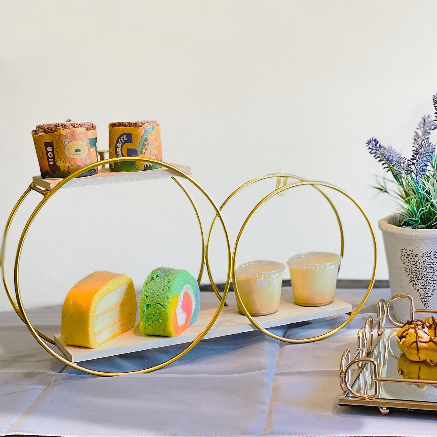 Gold 2-tier round floating shelf with desserts and drinks displayed elegantly.